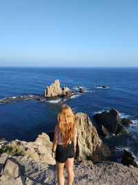 Rear view of woman looking at sea against clear sky