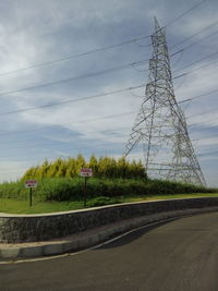 Electricity pylon against cloudy sky