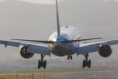 Airplane flying over airport runway against sky