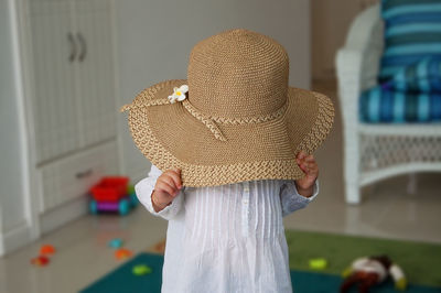 Baby girl playing peek a boo with sun hat