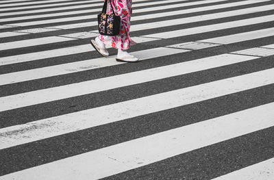 Low section of woman walking on zebra crossing