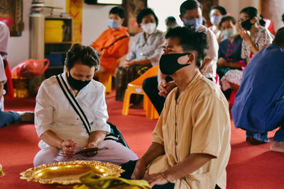 People wearing mask sitting at temple