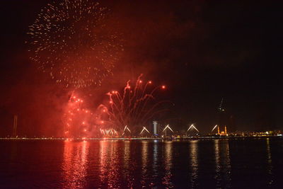 Firework display over river against sky