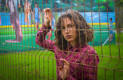 Portrait of girl standing against fence