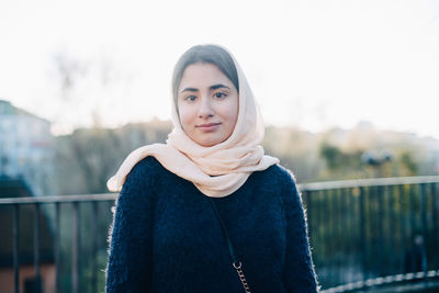 Portrait of confident teenage girl wearing hijab looking away against sky