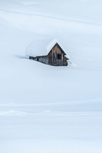 Snow covered house by building against sky