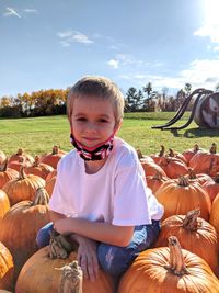 Portrait of boy sitting on pumpkin field