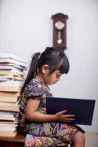 Side view of girl reading book at home