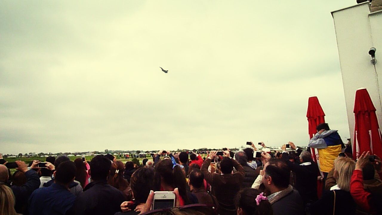 large group of people, flying, sky, men, lifestyles, leisure activity, crowd, person, cloud - sky, building exterior, flag, mid-air, architecture, built structure, bird, airplane, outdoors, mixed age range, city