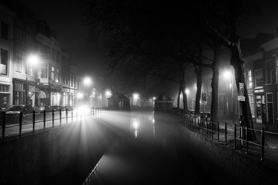 Canal amidst buildings at night