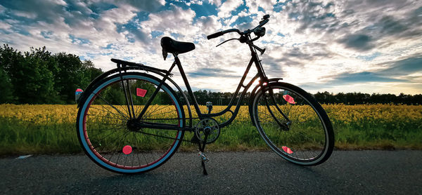 Bicycle parked on field against sky