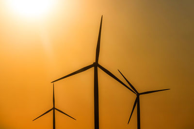 Low angle view of wind turbine against orange sky