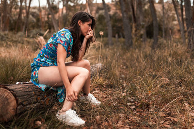Young woman looking away while sitting on land