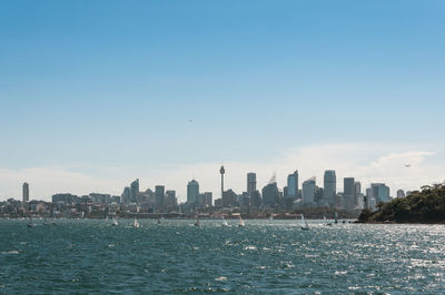 City buildings by sea against sky