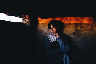 Portrait of young man standing against wall