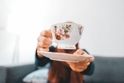 Woman holding coffee cup against sky