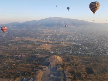 Aerial view of hot air balloons flying over landscape