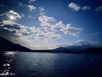 Scenic view of lake by silhouette mountains against sky