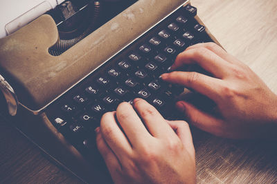 Cropped hands using typewriter on table 