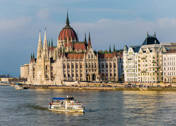 Touristic river barge on the danube in front of the parliament of budapest, hungary