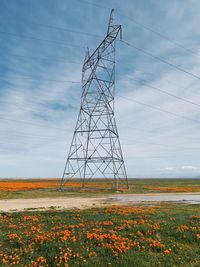 Electricity pylon on field against sky
