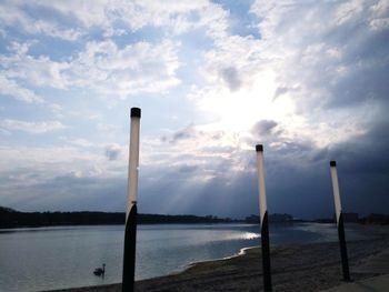 Wooden posts in lake against sky