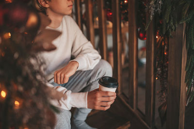 Portrait of candid authentic smiling handsome boy teenager using mobile phone at xmas home interior