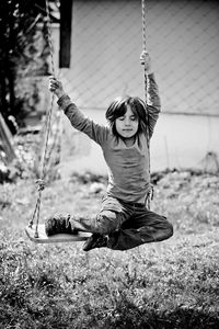 Full length of boy enjoying swing at playground