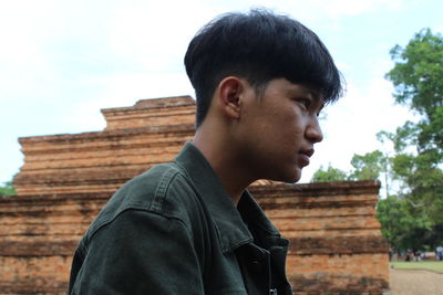 Portrait of young man looking away against sky