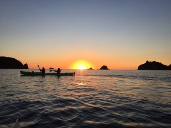 Silhouette people sailing on sea against sky during sunset