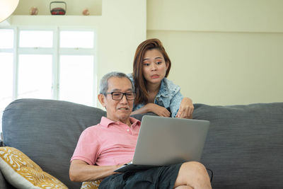 Young woman using mobile phone while sitting on sofa