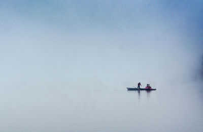 People in boat on sea against sky