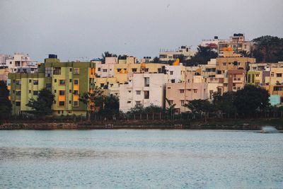 Buildings by lake side against clear sky