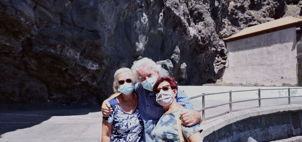 Portrait of friends wearing mask against bridge