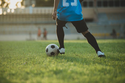 Low section of man playing soccer ball on grass