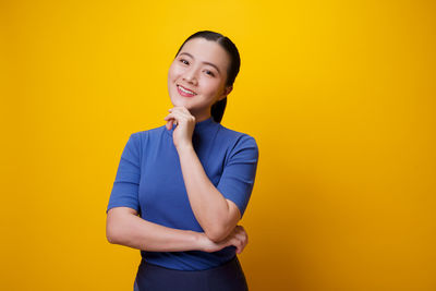 Portrait of a smiling young woman against yellow background