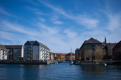 Buildings by river against sky in city