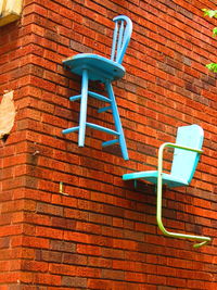 Low angle view of empty chair against brick wall