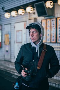 Portrait of young man standing against wall