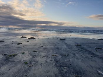 Surface level of beach against sky during sunset