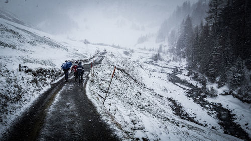 People walking on snowcapped mountain against sky