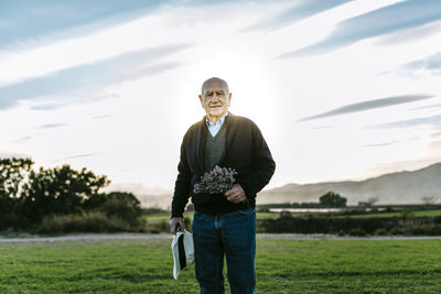Spain, tarragona, senior man with bouquet of flowers in the field