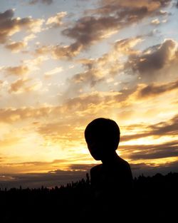 Silhouette boy against sky during sunset