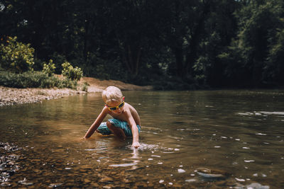 Full length of shirtless boy swimming in lake