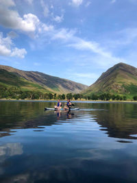 People on lake against sky