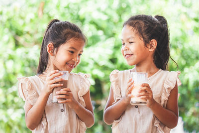 Friends having milk from glasses against trees