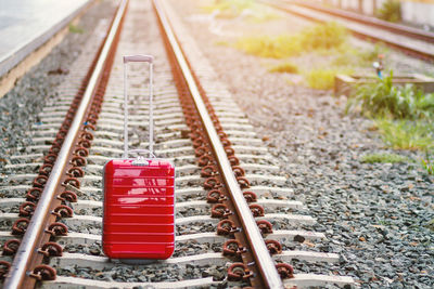 Red luggage on railroad track