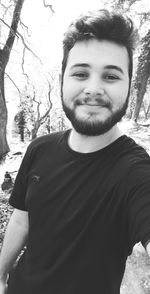 Portrait of young man standing against trees