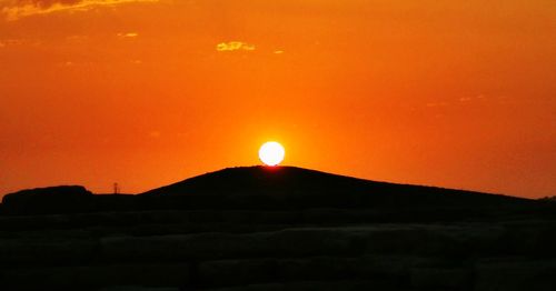 Scenic view of silhouette mountain against orange sky