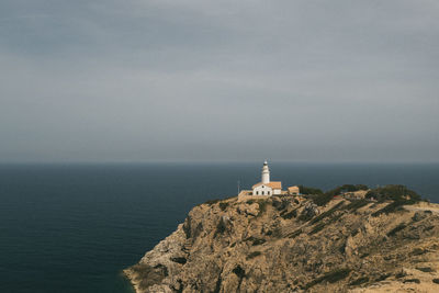 Lighthouse by sea against sky